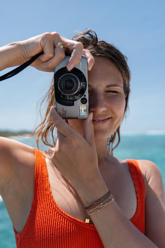Lächelnde Frau mit Filmkamera, im Hintergrund die Lagune
